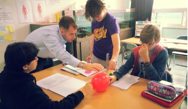 Middle school students at British International Academy in Geoje conducting a balloon-based science experiment with their teacher in a STEM classroom.