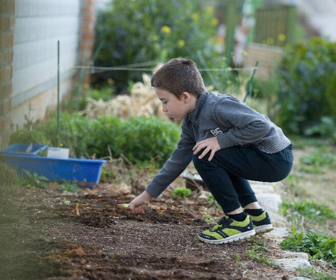 A young student at British International Academy in Geoje gardening outside, engaging in hands-on outdoor learning.